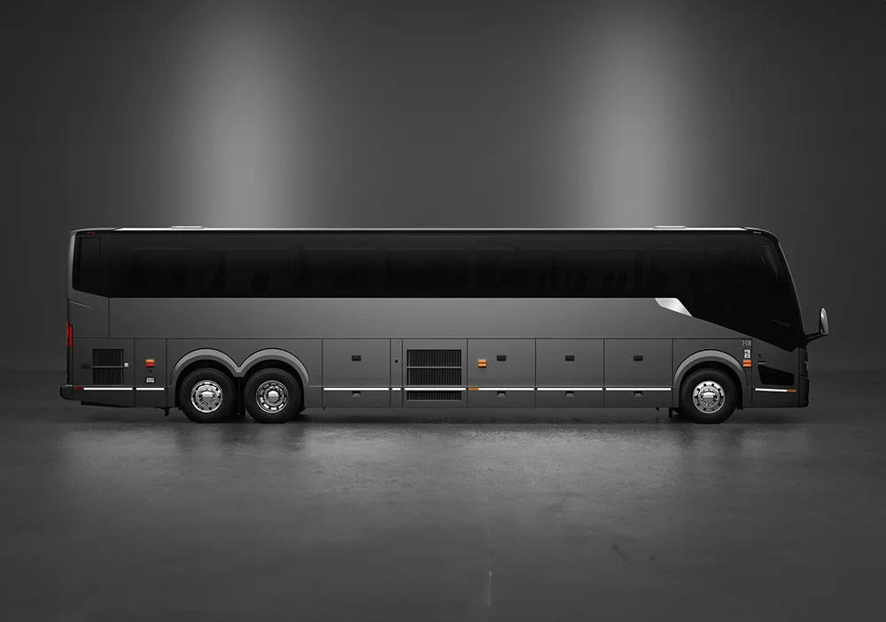 A modern, black coach bus with six wheels is parked in a studio with a plain, dark background.