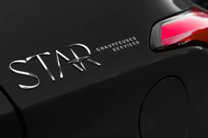 Close-up of a car with the words "STAR CHAUFFEURED SERVICES" in metallic letters next to a taillight and the fuel door.
