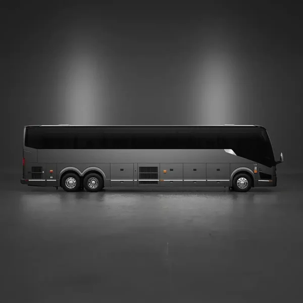 A modern, dark gray coach bus is parked indoors, shown in profile view against a plain, dimly lit background.